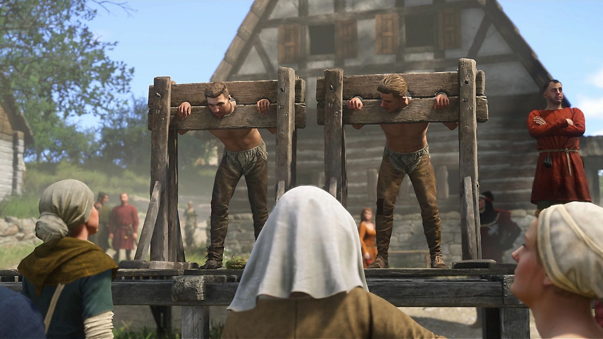 Two people in the stocks with a crowd gathered around them in Kingdom Come: Deliverance 2