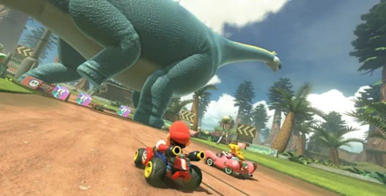 Mario Kart World: Mario and other racers drive along a dirt track beneath a giant dinosaur statue.