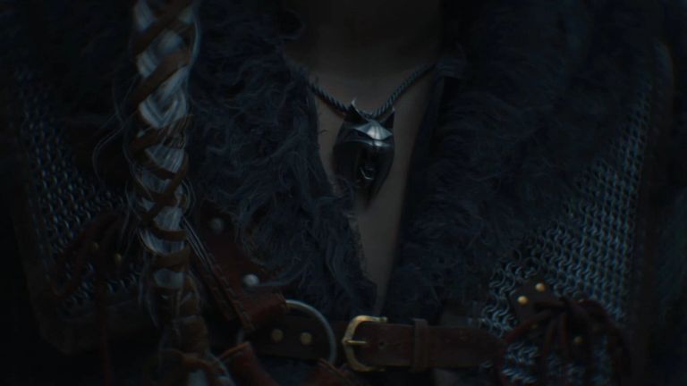 The Witcher IV: Close-up of a silver wolf medallion, chain mail, and a fur-lined garment.
