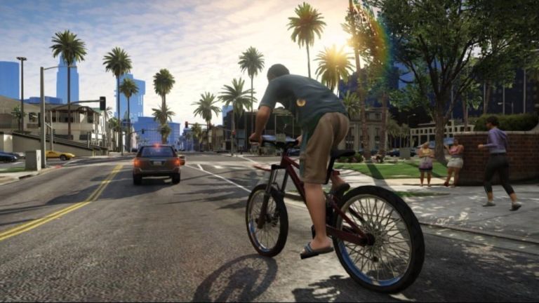 A cyclist rides along a palm-lined city street with cars nearby.