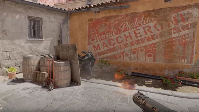 Counter-Strike 2: A soldier crouches beside barrels near flames in a courtyard.