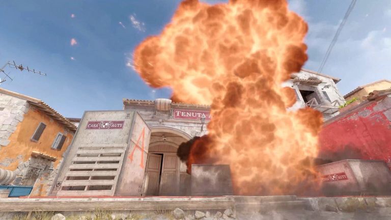Counter-Strike 2: A fireball rises in a village square among stone buildings and crates.
