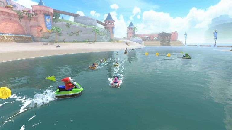 Mario Kart World: Racers drive through shallow water beside a sandy beach, castle, and floating coins.
