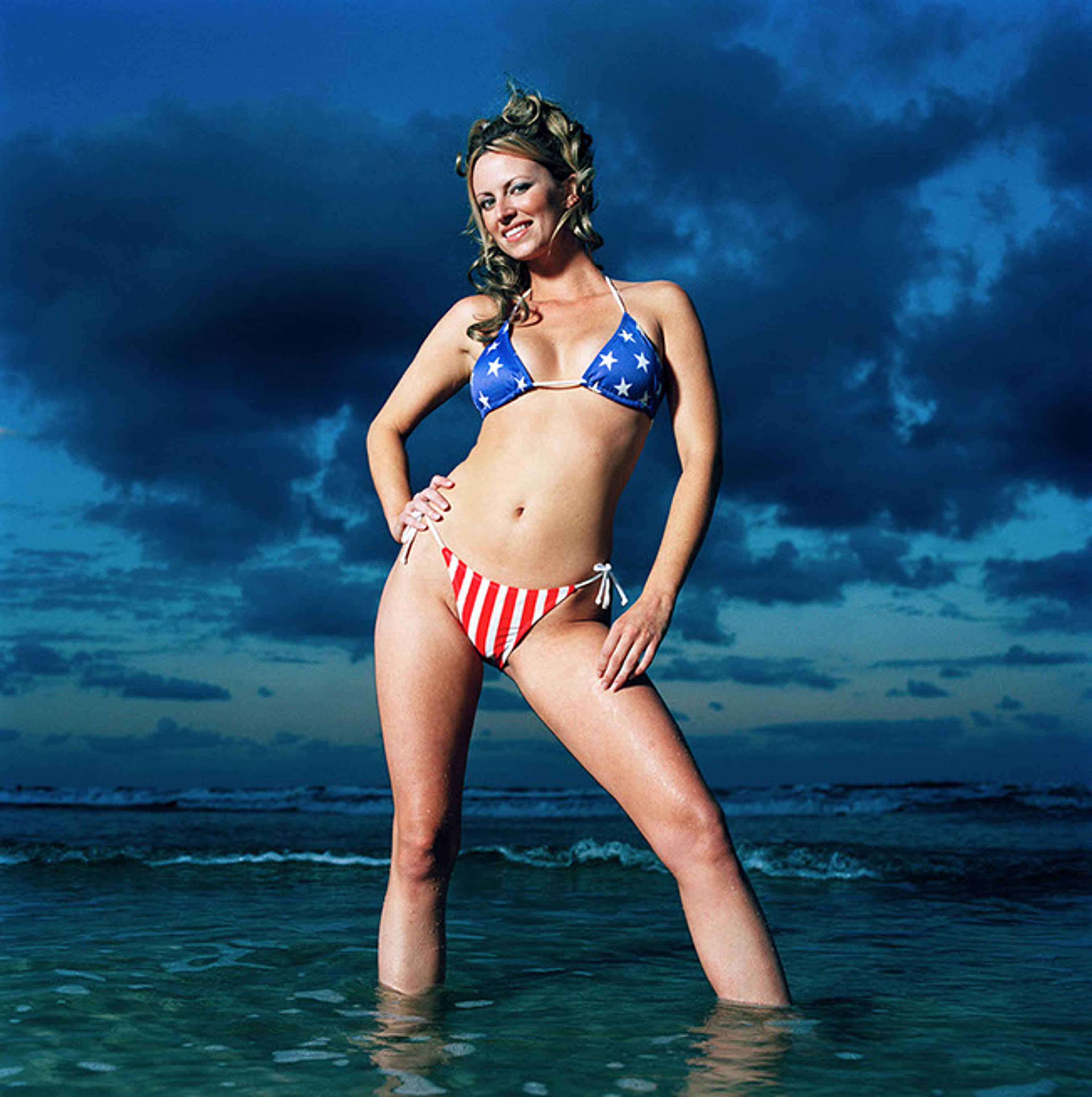 Junge Frau posiert in Stars and Stripes Bikini in seichter Brandung
