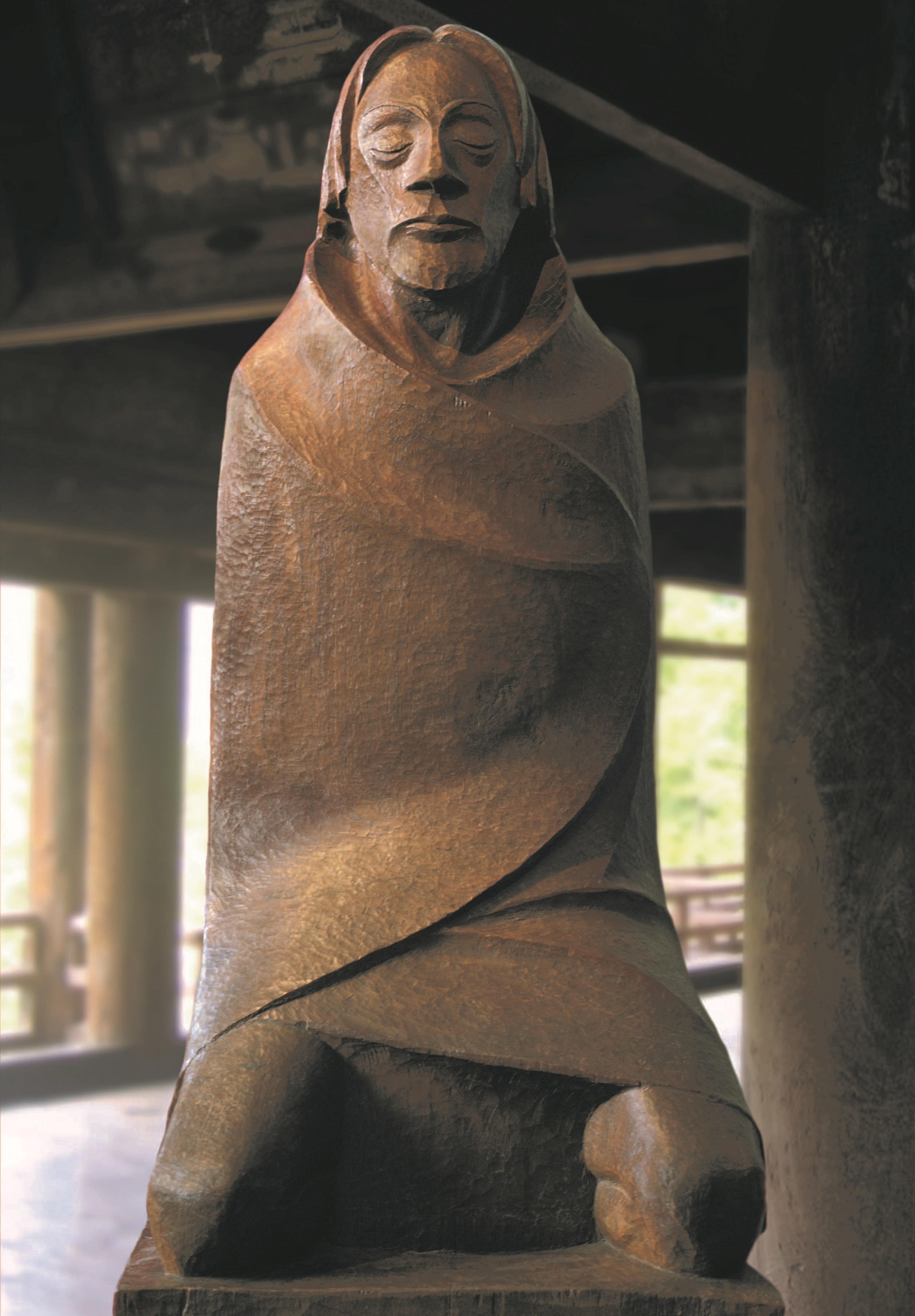 Holzskulptur stellt einen knieenden Mann dar