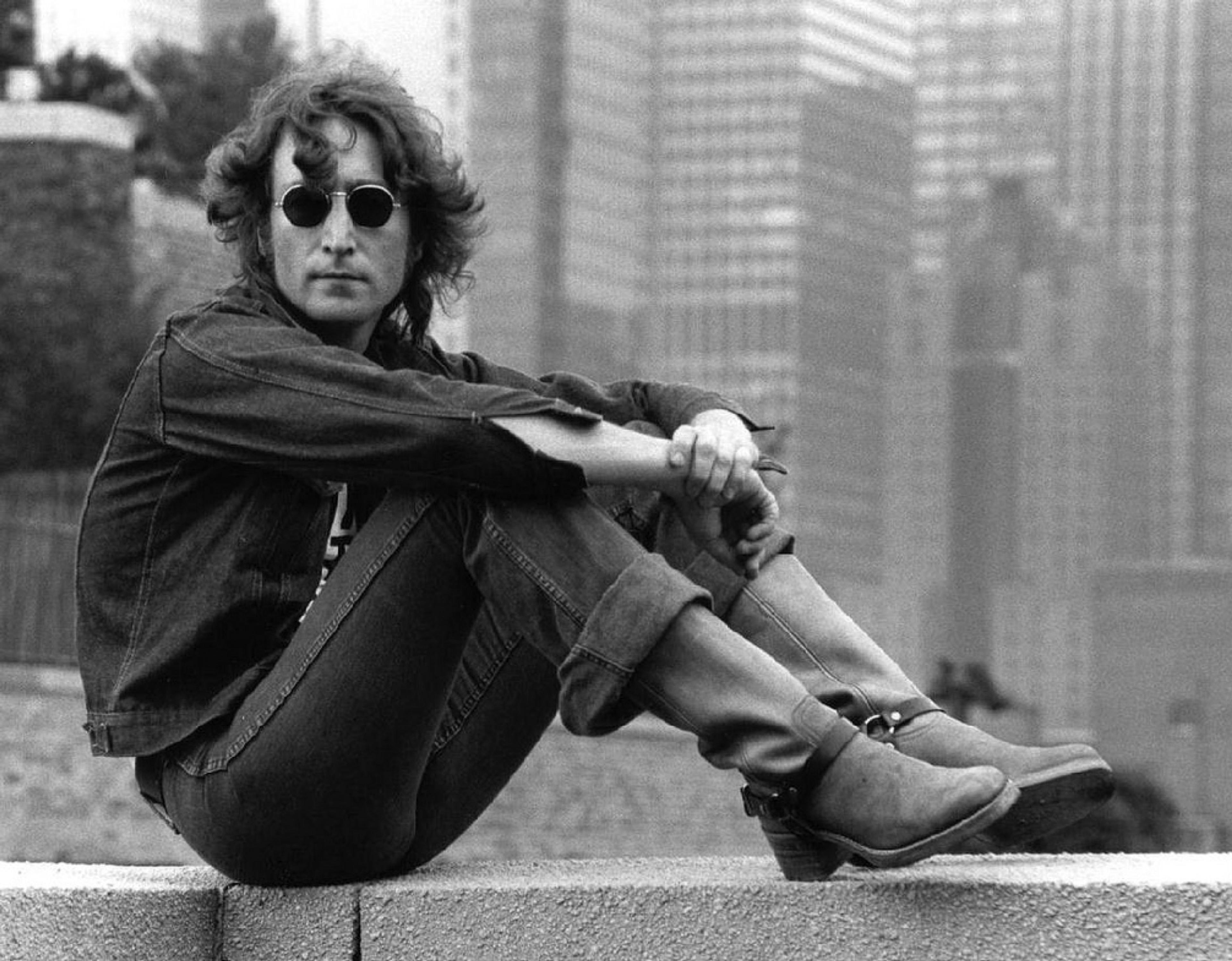 John Lennon auf einer Mauer sitzend