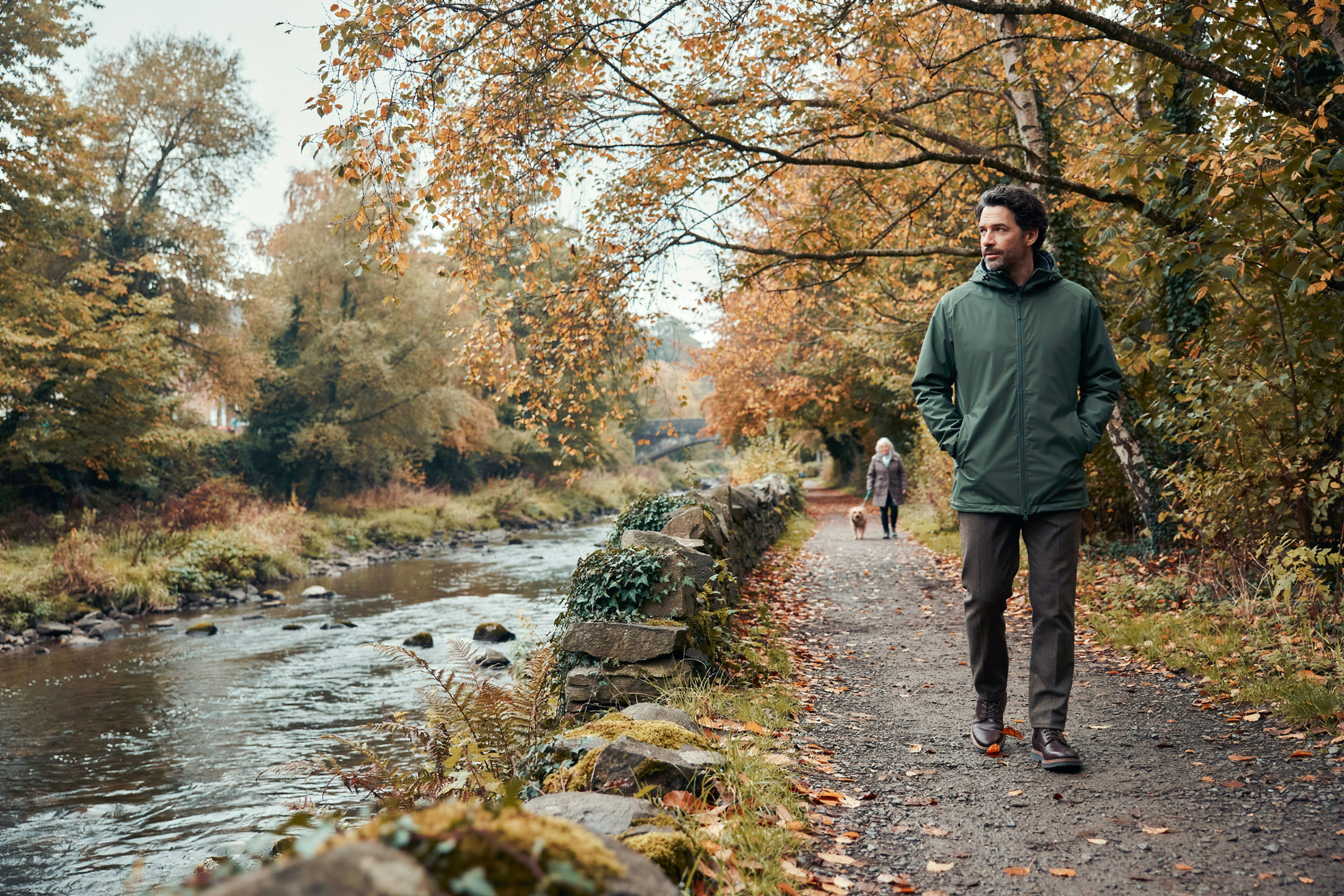 Adult walking through Colinton Dell in Edinburgh in autumn, someone checking whether their treatment qualifies them for a free COVID-19 vaccine