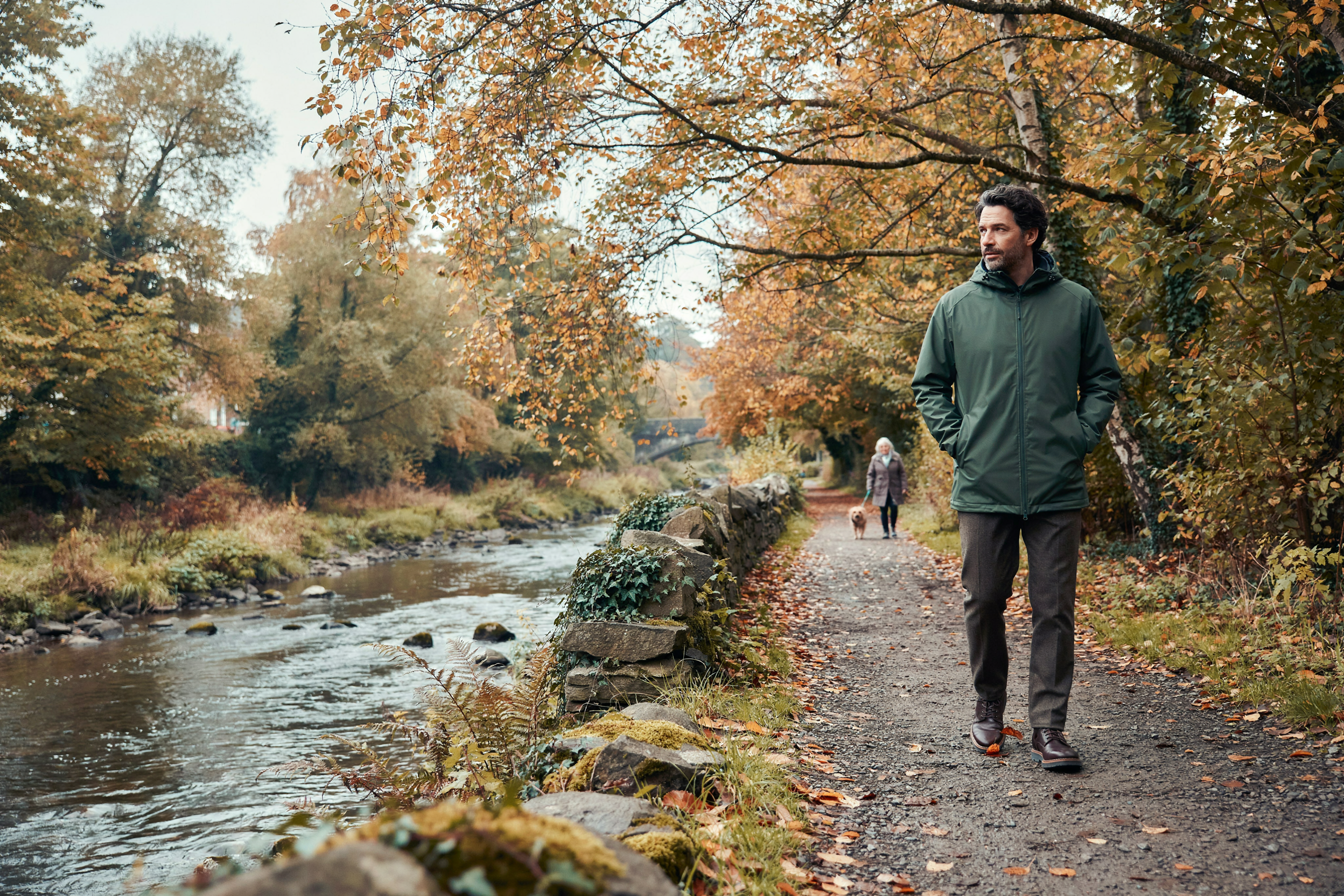 Adult walking through Colinton Dell in Edinburgh in autumn, someone checking whether their treatment qualifies them for a free COVID-19 vaccine