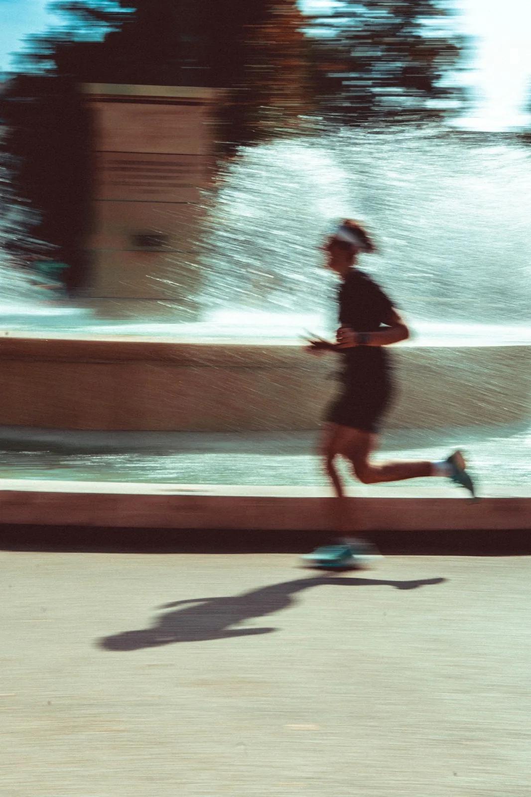 A man running down a street next to a fountain