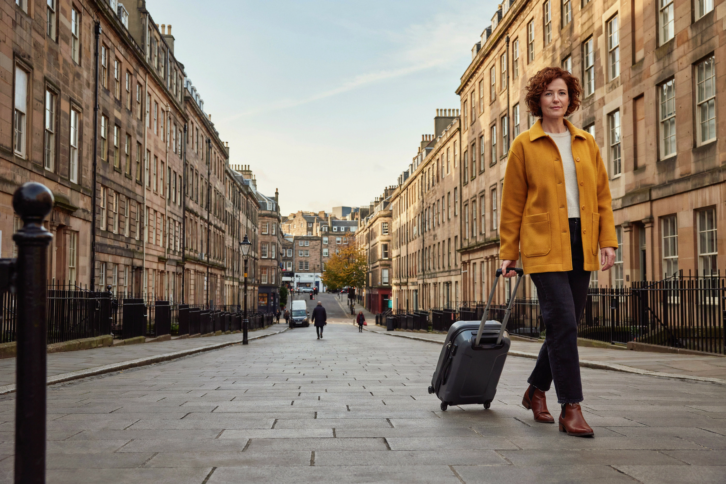 Adult setting off on a trip from Edinburgh's New Town with a small suitcase, having timed their COVID-19 vaccine two weeks before travel