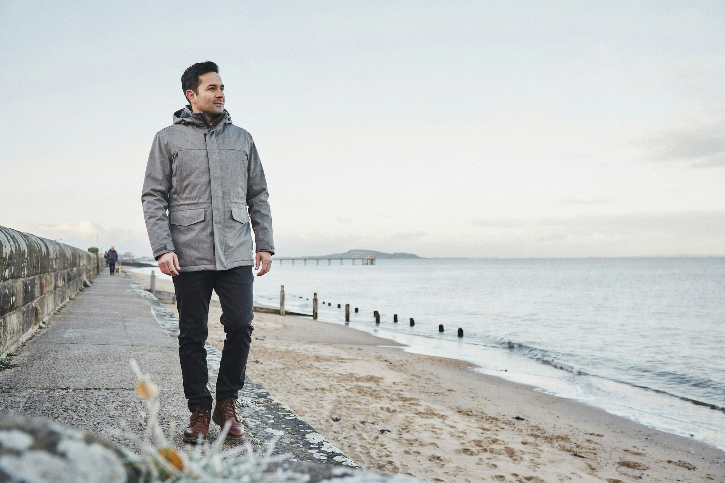 Adult walking the Cramond promenade in Edinburgh on a winter morning after checking a COVID-19 vaccine was suitable for them