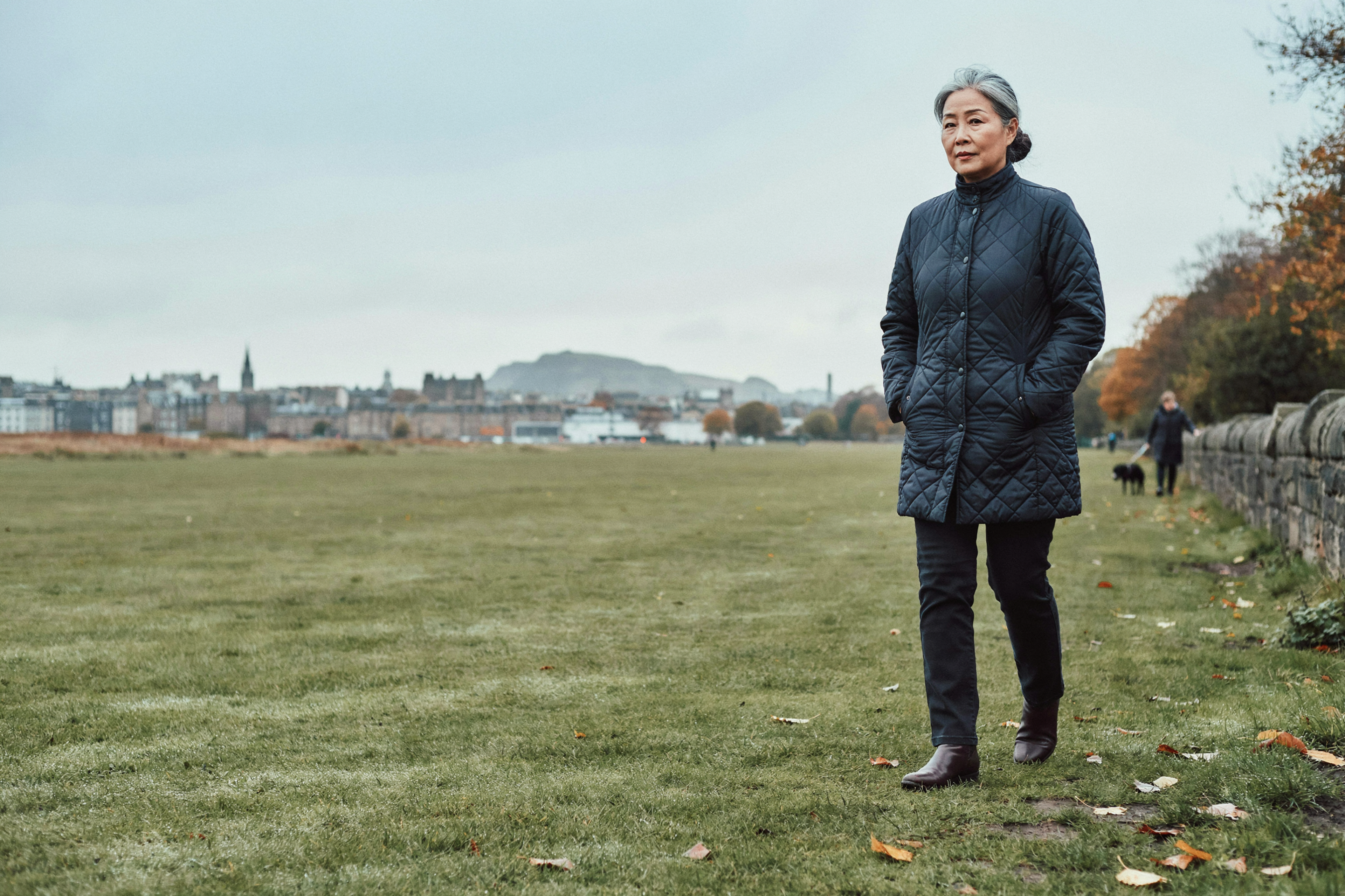 Adult walking across Bruntsfield Links in Edinburgh on a calm autumn morning, settled and thoughtful about their care