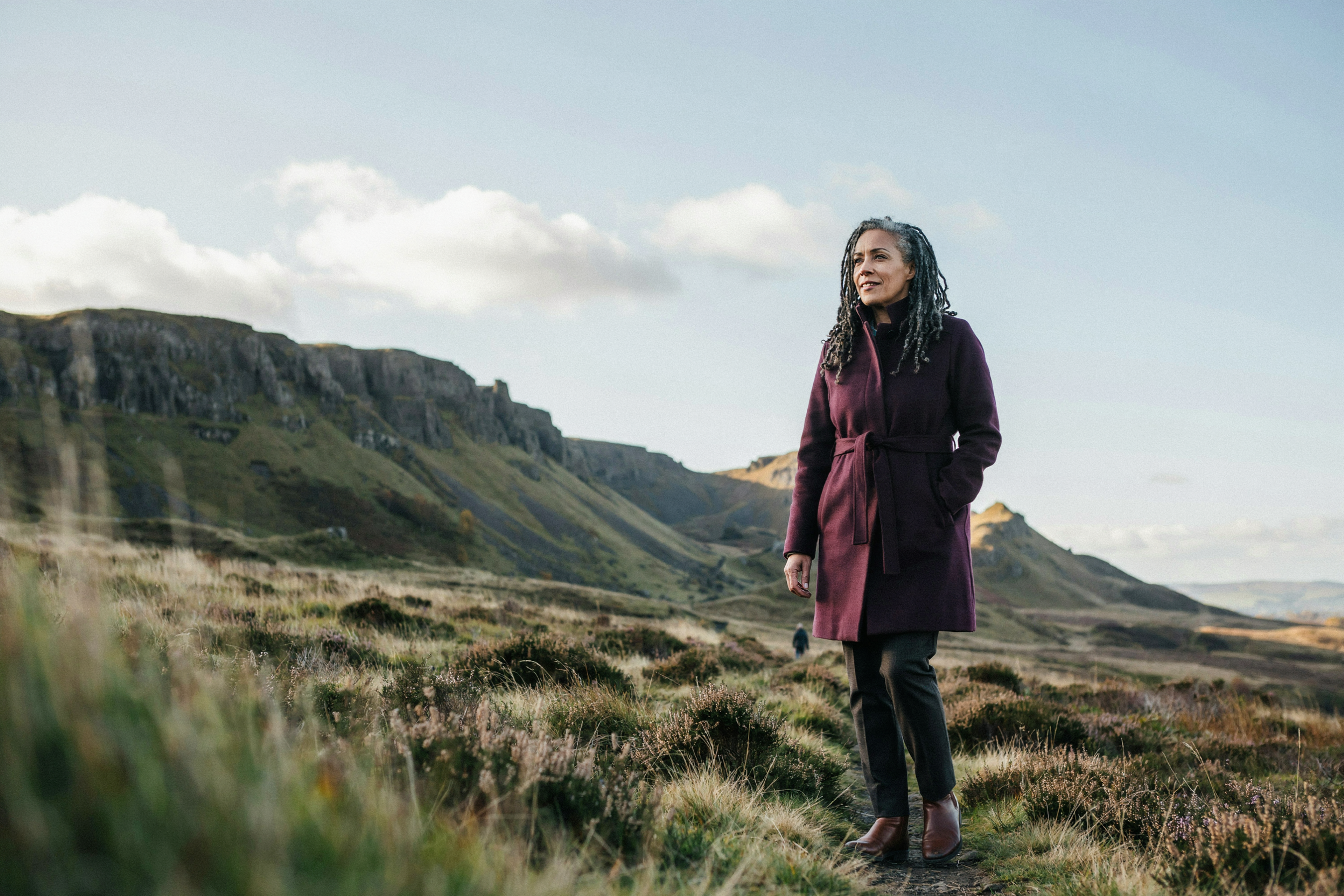 Adult walking through Holyrood Park in Edinburgh beneath Arthur's Seat, relaxed and confident about their treatment plan
