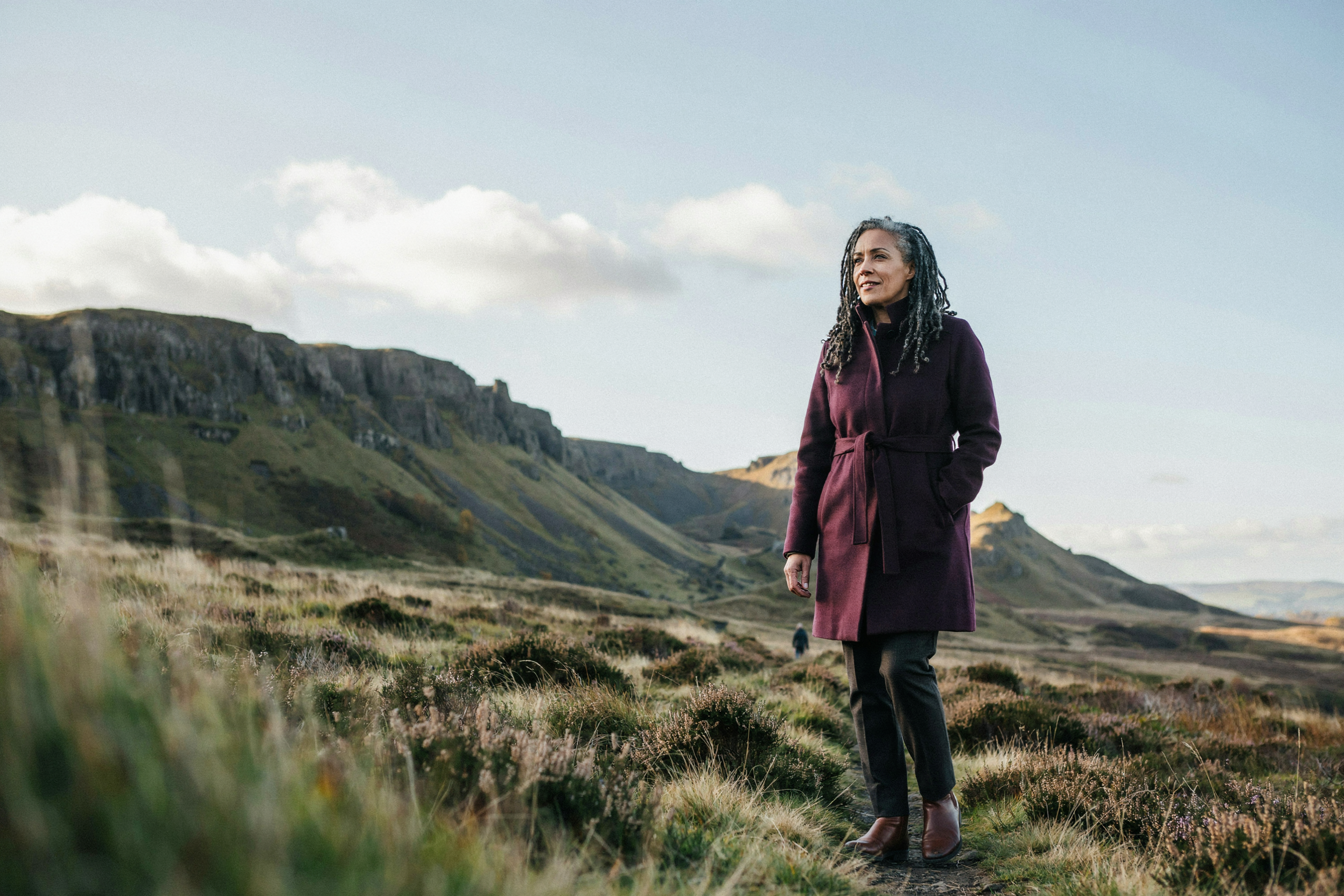 Adult walking through Holyrood Park in Edinburgh beneath Arthur's Seat, relaxed and confident about their treatment plan