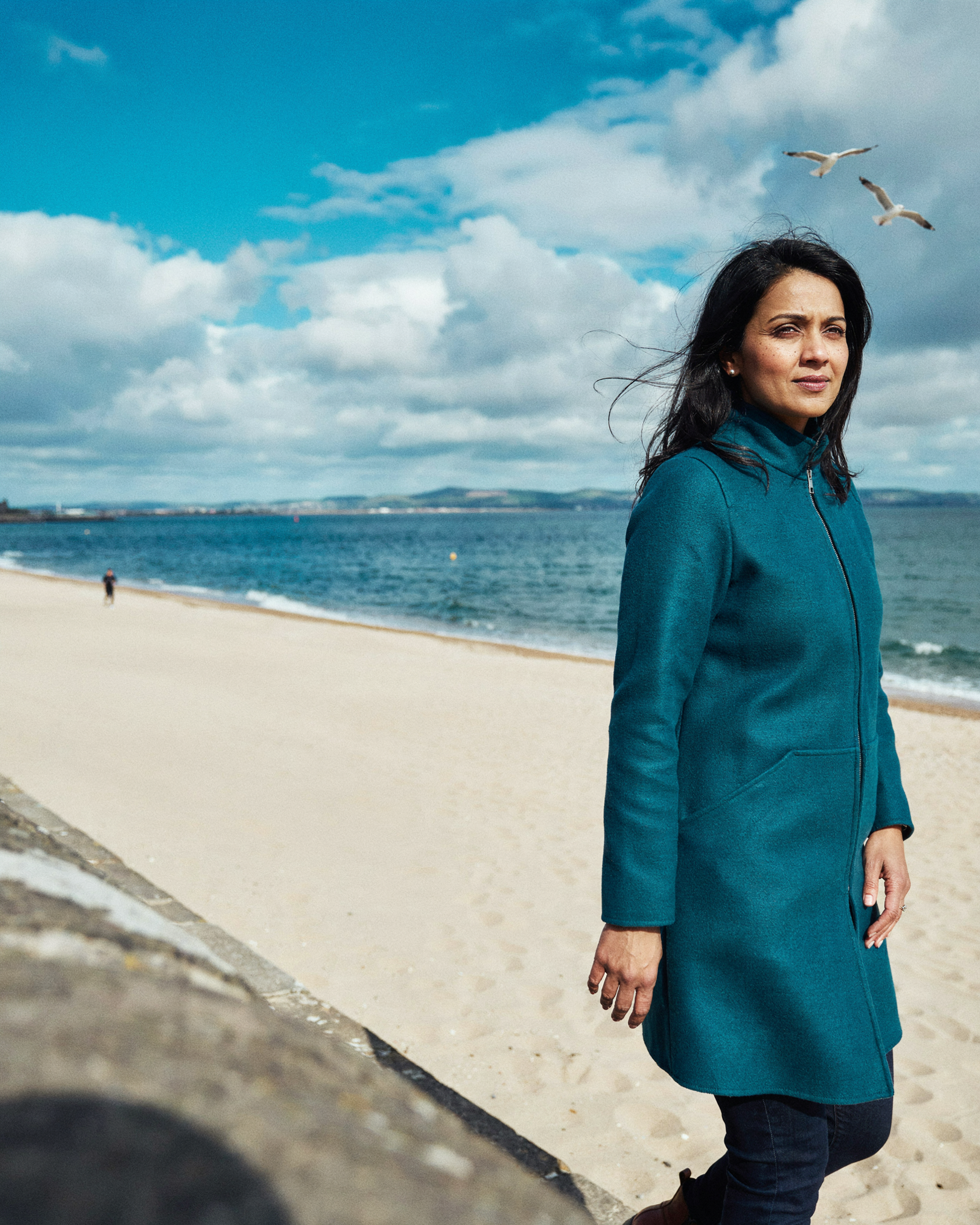 Adult walking the Portobello promenade in Edinburgh on a bright winter day, protected later in the flu season