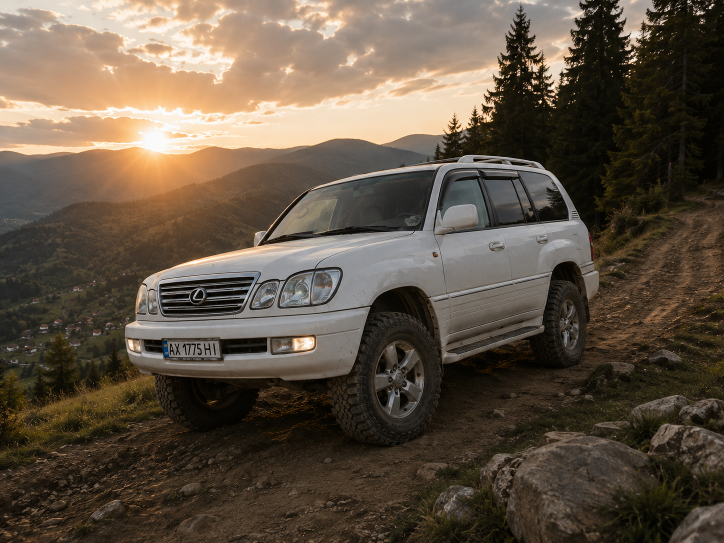 Lexus LX 470 білого кольору на ґрунтовій гірській дорозі серед смерек