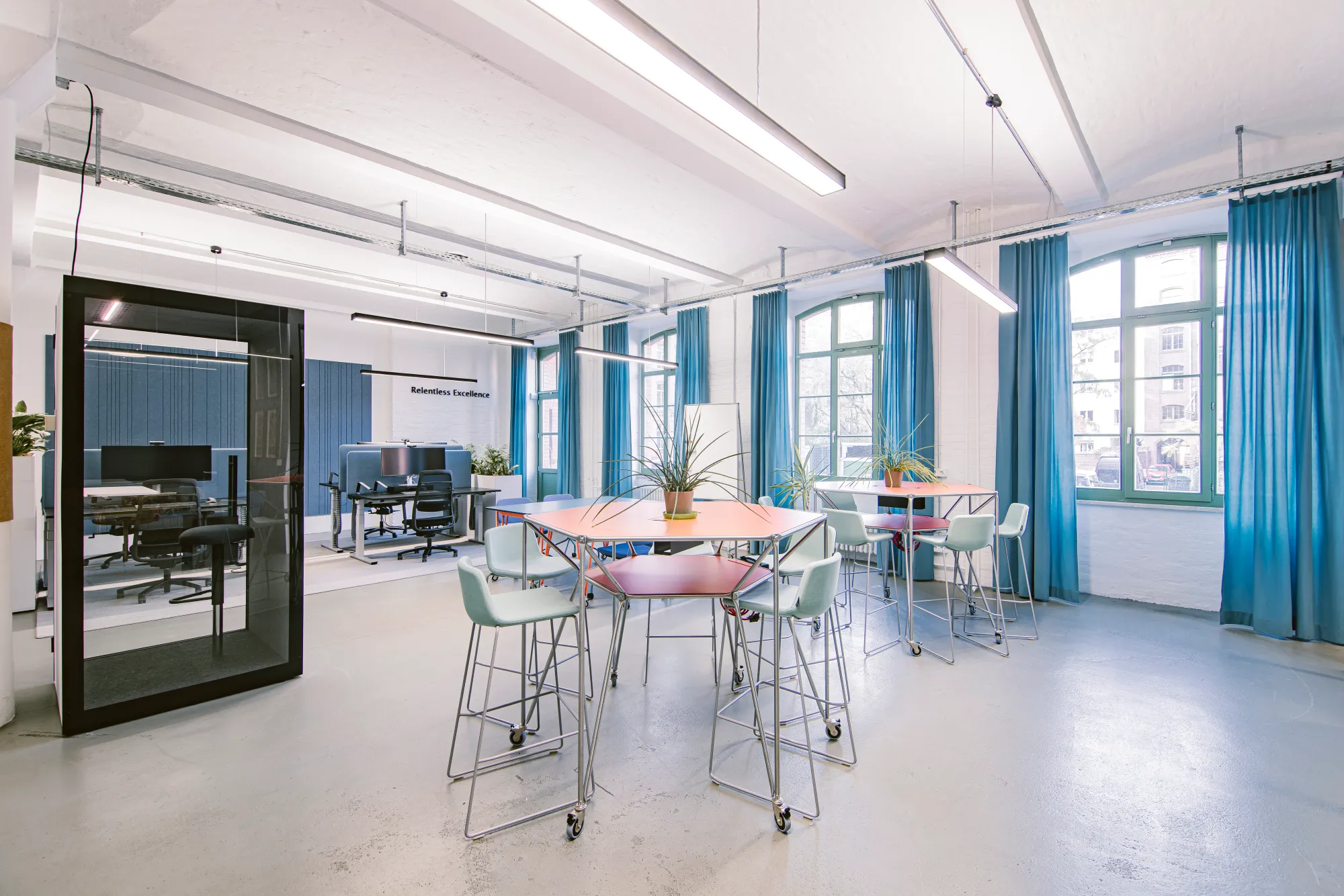 Lichtdurchflutetes Office mit blauen Vorhängen, Besprechungskabine und Gruppenzonen