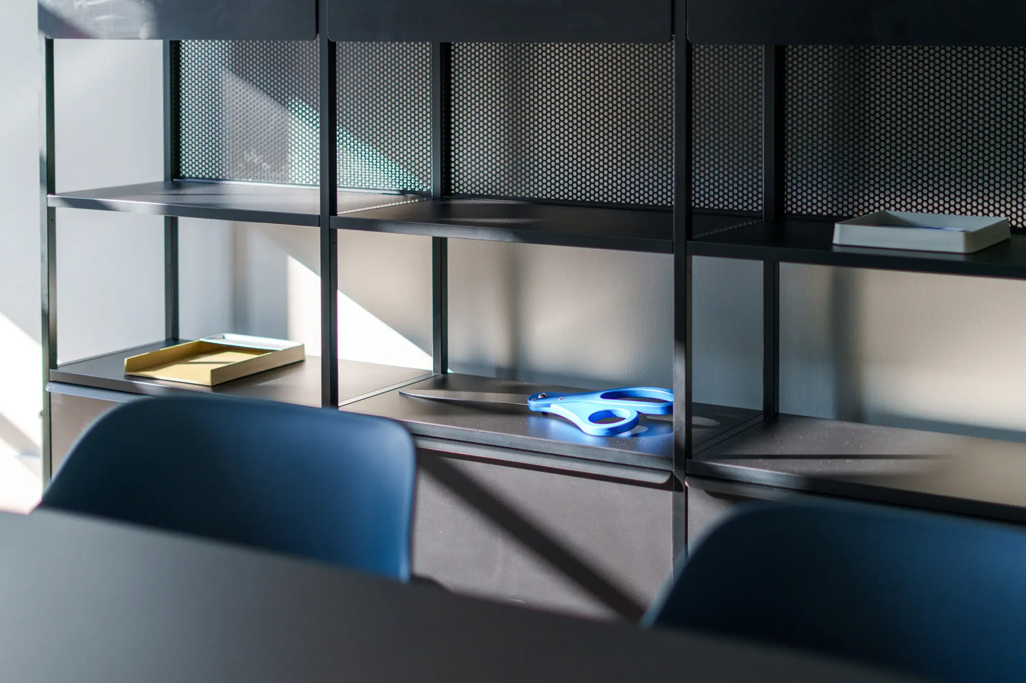Zwei Konferenzstühle mit einem schwarzen Sideboard als Stauraumlösung im Hintergrund