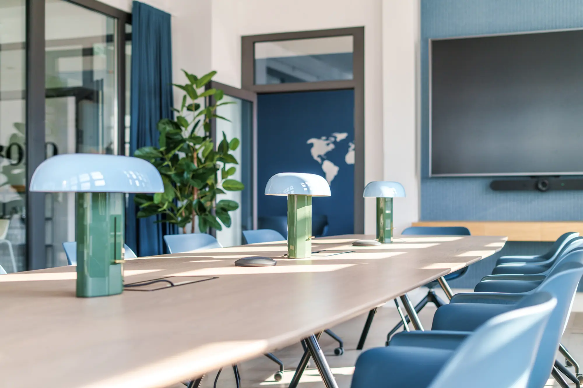 Heller Konferenzraum mit großem Monitor und Holzmöbeln sowie Designerleuchten