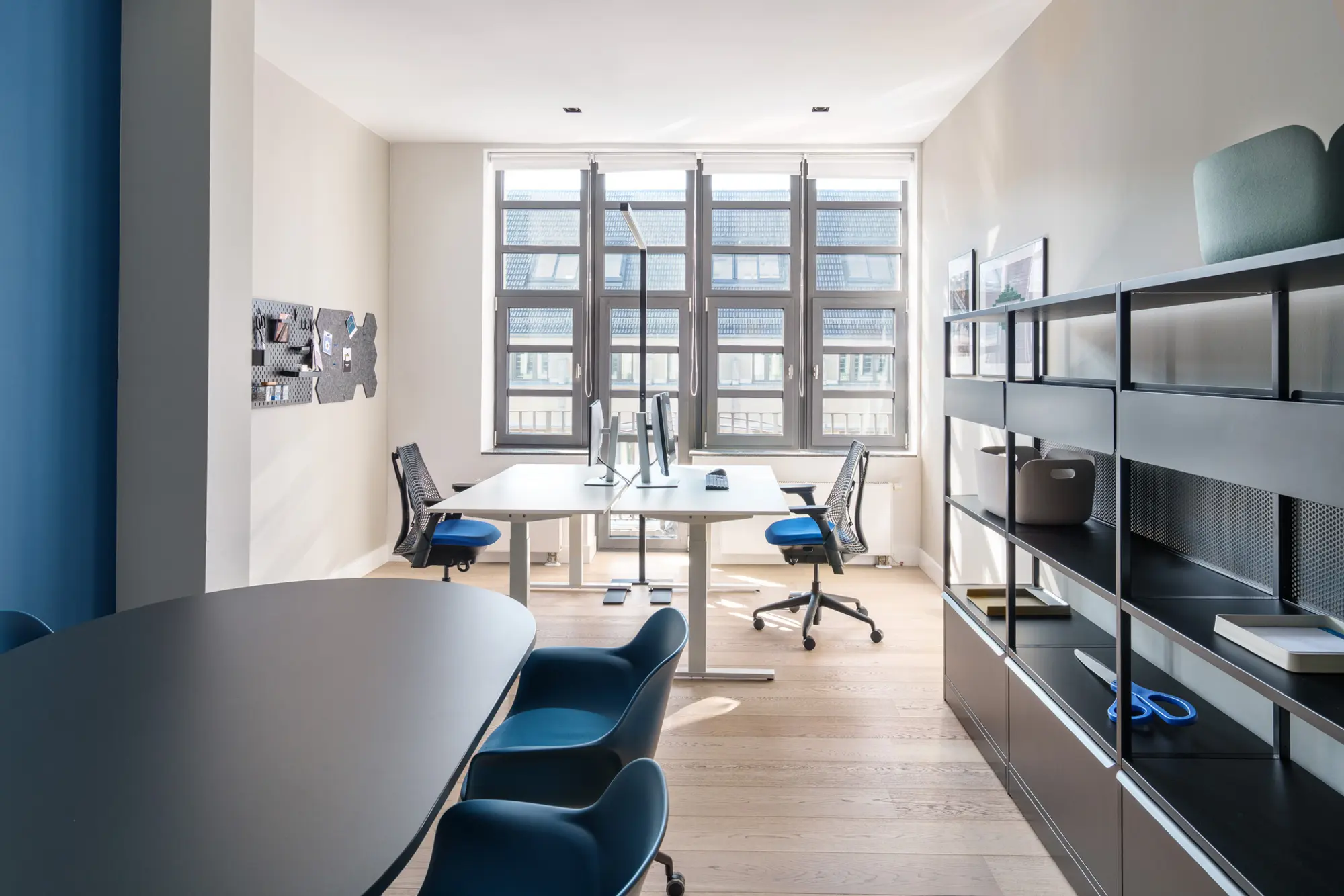 Office Bereich mit großen Fenstern und dunklen Möbeln mit blauen Akzentfarben