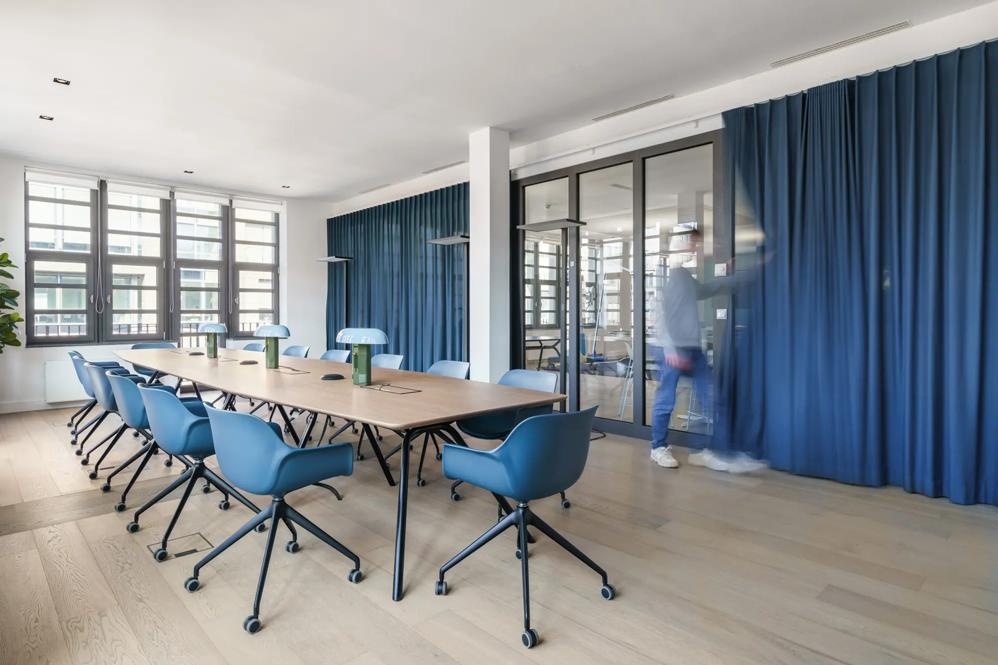 Konferenzraum mit Laminatboden, großem Konferenztisch und blauen Büromöbeln