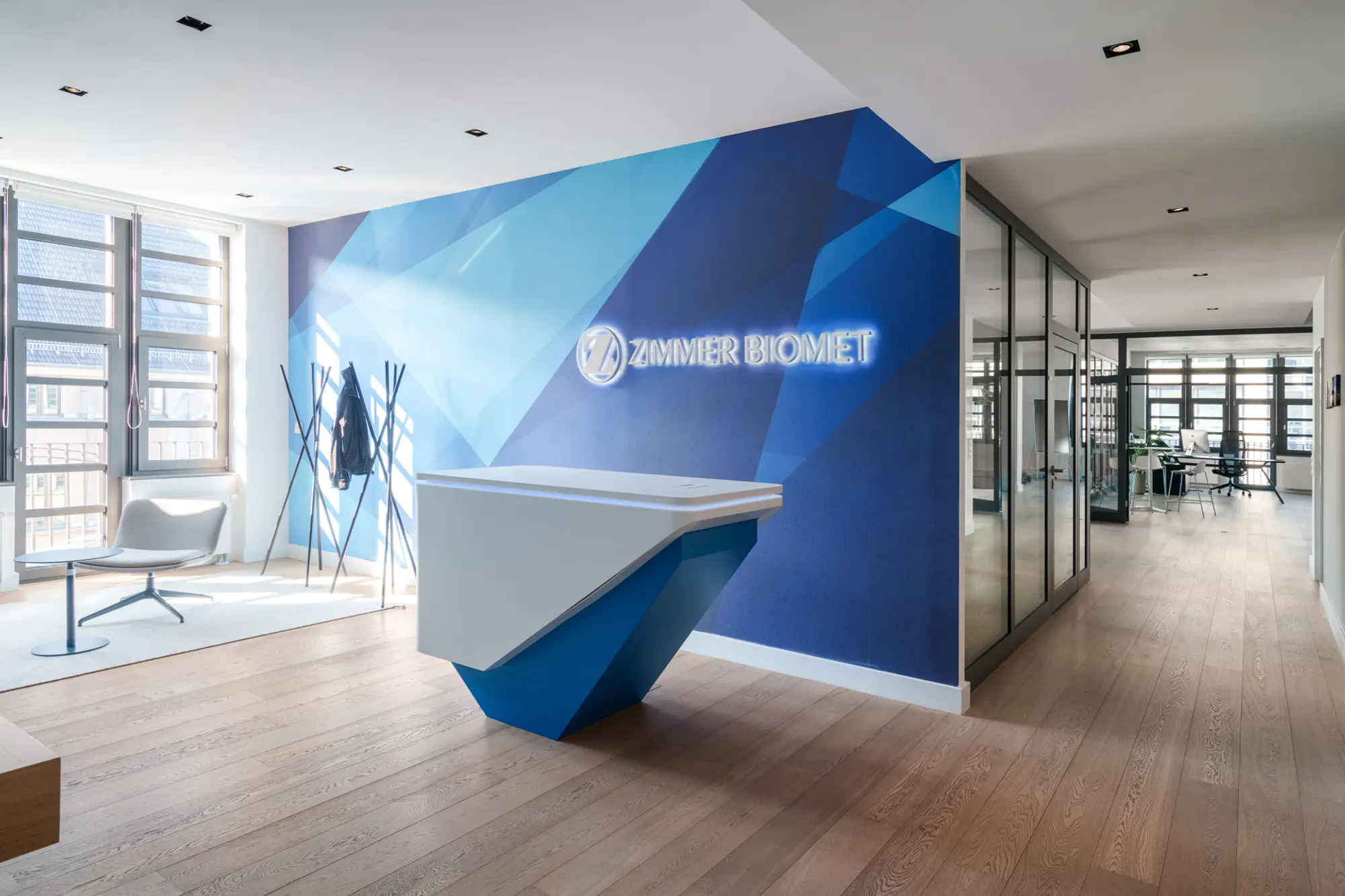Weißer Empfangstresen mit Zimmer Biomet Logo an blauer Wand