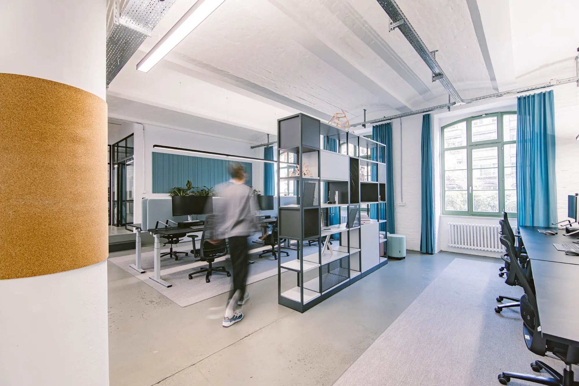 Arbeitsplatzbereich mit blauen Vorhängen und Regal als Trenner