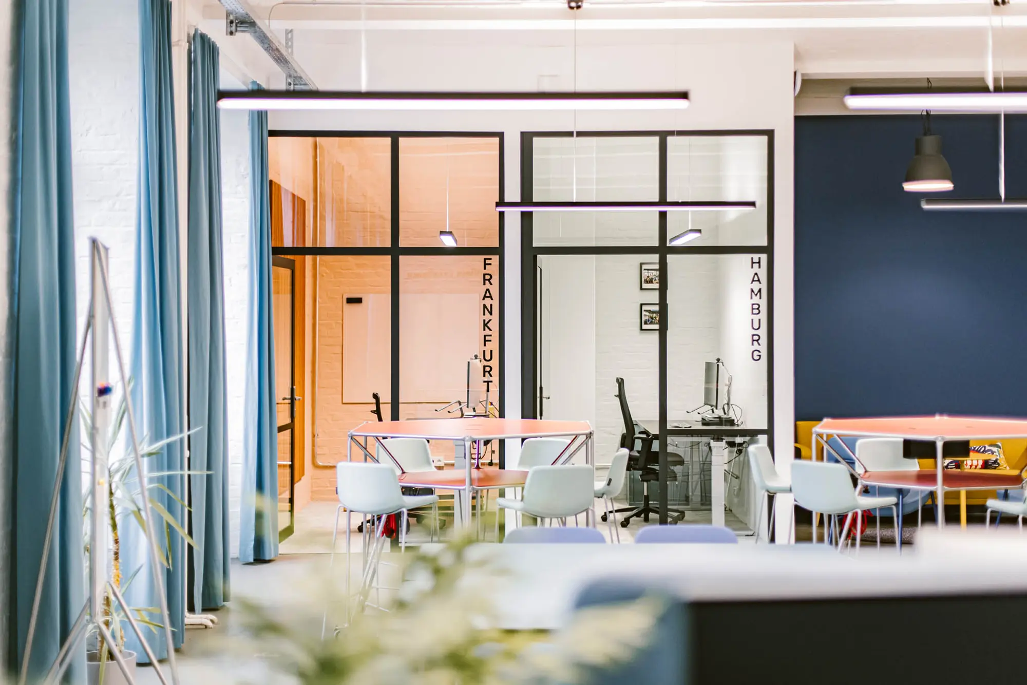 Zwei Meetingräume in unterschiedlichen Farben und ein Lounge Bereich innerhalb eines Open Space Büros