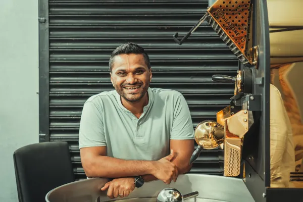 a man is sitting in front of a coffee machine and smiling .