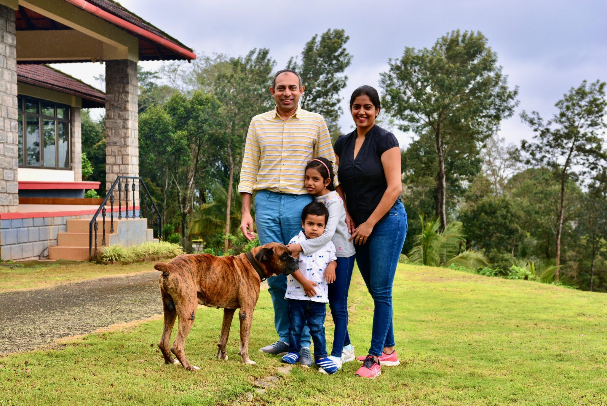 a family and their dog are posing for a picture in front of a house .