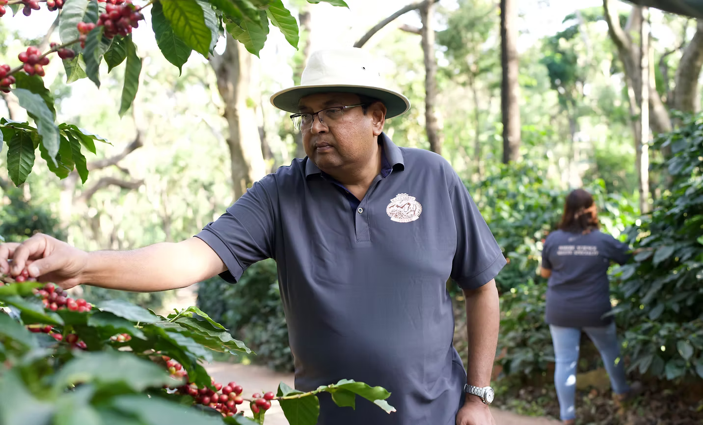 A man in a hat examines red coffee cherries on a plant, with another person working in the background.​​​​‌﻿‍﻿​‍​‍‌‍﻿﻿‌﻿​‍‌‍‍‌‌‍‌﻿‌‍‍‌‌‍﻿‍​‍​‍​﻿‍‍​‍​‍‌﻿​﻿‌‍​‌‌‍﻿‍‌‍‍‌‌﻿‌​‌﻿‍‌​‍﻿‍‌‍‍‌‌‍﻿﻿​‍​‍​‍﻿​​‍​‍‌‍‍​‌﻿​‍‌‍‌‌‌‍‌‍​‍​‍​﻿‍‍​‍​‍‌‍‍​‌﻿‌​‌﻿‌​‌﻿​​‌﻿​﻿​﻿‍‍​‍﻿﻿​‍﻿﻿‌﻿​﻿‌‍﻿﻿​‍﻿‌‌﻿​﻿‌‍​‌‌‍﻿‍‌‍‍‌‌﻿‌​‌﻿‍‌​‍﻿‌‌‍﻿‍‌‍‌‌‌﻿‍​‌﻿‌​‌‍‍‍‌﻿​﻿​‍﻿‌‌﻿‌​‌‍​‌‌﻿‌﻿‌‍﻿‍‌﻿‍‌​‍﻿‍‌﻿‌‍‌‍‌‌‌﻿​‍‌‍​﻿‌‍‌‌‌‍﻿​​‍﻿‍‌‍​‌‌﻿​​‌﻿​​​‍﻿﻿‌‍‍‌‌‍﻿‍‌﻿‌​‌‍‌‌‌‍﻿‍‌﻿‌​​‍﻿﻿‌‍‌‌‌‍‌​‌‍‍‌‌﻿‌​​‍﻿﻿‌‍﻿‌‌‍﻿﻿‌‍‌​‌‍‌‌​﻿﻿‌‌﻿​​‌﻿​‍‌‍‌‌‌﻿​﻿‌‍‌‌‌‍﻿‍‌﻿‌​‌‍​‌‌﻿‌​‌‍‍‌‌‍﻿﻿‌‍﻿‍​﻿‍﻿‌‍‍‌‌‍‌​​﻿﻿‌​﻿‍‌‌‍‌‌‌‍‌‍​﻿‌​‌‍​﻿‌‍‌​​﻿‍‌​﻿​﻿​‍﻿‌​﻿‌﻿‌‍‌​​﻿‌‌‌‍​‍​‍﻿‌​﻿‌​​﻿​‍‌‍‌​​﻿​‌​‍﻿‌​﻿‍​‌‍​‍‌‍​‍​﻿​‍​‍﻿‌​﻿​​​﻿‍‌​﻿‍‌​﻿​﻿​﻿‌‌​﻿​‌​﻿​﻿‌‍​‌​﻿‌​​﻿‌‌‌‍​‌​﻿‌‌​﻿‍﻿‌﻿‌​‌﻿‍‌‌﻿​​‌‍‌‌​﻿﻿‌‌﻿​​‌‍﻿﻿‌﻿​﻿‌﻿‌​​﻿‍﻿‌﻿​​‌‍​‌‌﻿‌​‌‍‍​​﻿﻿‌‌‍​﻿‌‍﻿﻿‌﻿‌‍‌‍‌‌‌﻿​‍‌​‍‌‌‍﻿‌‌‍​‌‌‍‌﻿‌‍‌‌​‍﻿‍‌‍​‌‌‍﻿​‌﻿‌​​﻿﻿﻿‌‍​‍‌‍​‌‌﻿​﻿‌‍‌‌‌‌‌‌‌﻿​‍‌‍﻿​​﻿﻿‌‌‍‍​‌﻿‌​‌﻿‌​‌﻿​​‌﻿​﻿​‍‌‌​﻿​﻿‌​​‌​‍‌‌​﻿​‍‌​‌‍​‍‌‌​﻿​‍‌​‌‍‌﻿​﻿‌‍﻿﻿​‍﻿‌‌﻿​﻿‌‍​‌‌‍﻿‍‌‍‍‌‌﻿‌​‌﻿‍‌​‍﻿‌‌‍﻿‍‌‍‌‌‌﻿‍​‌﻿‌​‌‍‍‍‌﻿​﻿​‍﻿‌‌﻿‌​‌‍​‌‌﻿‌﻿‌‍﻿‍‌﻿‍‌​‍﻿‍‌﻿‌‍‌‍‌‌‌﻿​‍‌‍​﻿‌‍‌‌‌‍﻿​​‍﻿‍‌‍​‌‌﻿​​‌﻿​​​‍‌‍‌‍‍‌‌‍‌​​﻿﻿‌​﻿‍‌‌‍‌‌‌‍‌‍​﻿‌​‌‍​﻿‌‍‌​​﻿‍‌​﻿​﻿​‍﻿‌​﻿‌﻿‌‍‌​​﻿‌‌‌‍​‍​‍﻿‌​﻿‌​​﻿​‍‌‍‌​​﻿​‌​‍﻿‌​﻿‍​‌‍​‍‌‍​‍​﻿​‍​‍﻿‌​﻿​​​﻿‍‌​﻿‍‌​﻿​﻿​﻿‌‌​﻿​‌​﻿​﻿‌‍​‌​﻿‌​​﻿‌‌‌‍​‌​﻿‌‌​‍‌‍‌﻿‌​‌﻿‍‌‌﻿​​‌‍‌‌​﻿﻿‌‌﻿​​‌‍﻿﻿‌﻿​﻿‌﻿‌​​‍‌‍‌﻿​​‌‍​‌‌﻿‌​‌‍‍​​﻿﻿‌‌‍​﻿‌‍﻿﻿‌﻿‌‍‌‍‌‌‌﻿​‍‌​‍‌‌‍﻿‌‌‍​‌‌‍‌﻿‌‍‌‌​‍﻿‍‌‍​‌‌‍﻿​‌﻿‌​​‍​‍‌﻿﻿‌