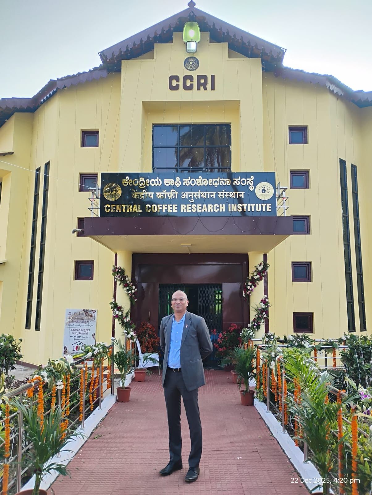 A man stands in front of the decorated Central Coffee Research Institute (CCRI) building.