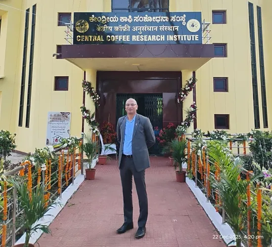 A man stands in front of the decorated Central Coffee Research Institute (CCRI) building.