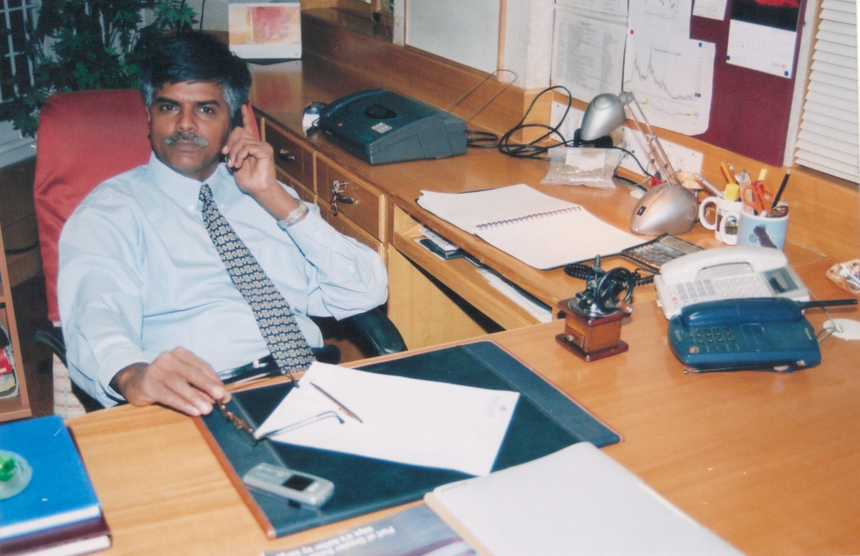 a man sits at a desk talking on a cell phone