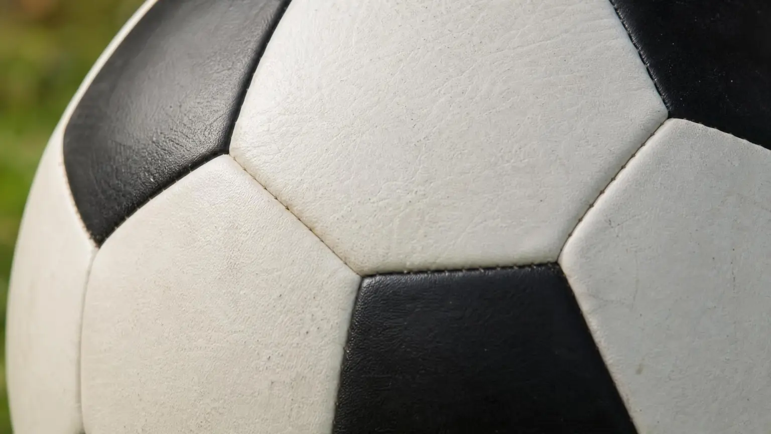 Close-up of a classic black-and-white soccer ball showing the stitched seams between its hexagon and pentagon panels