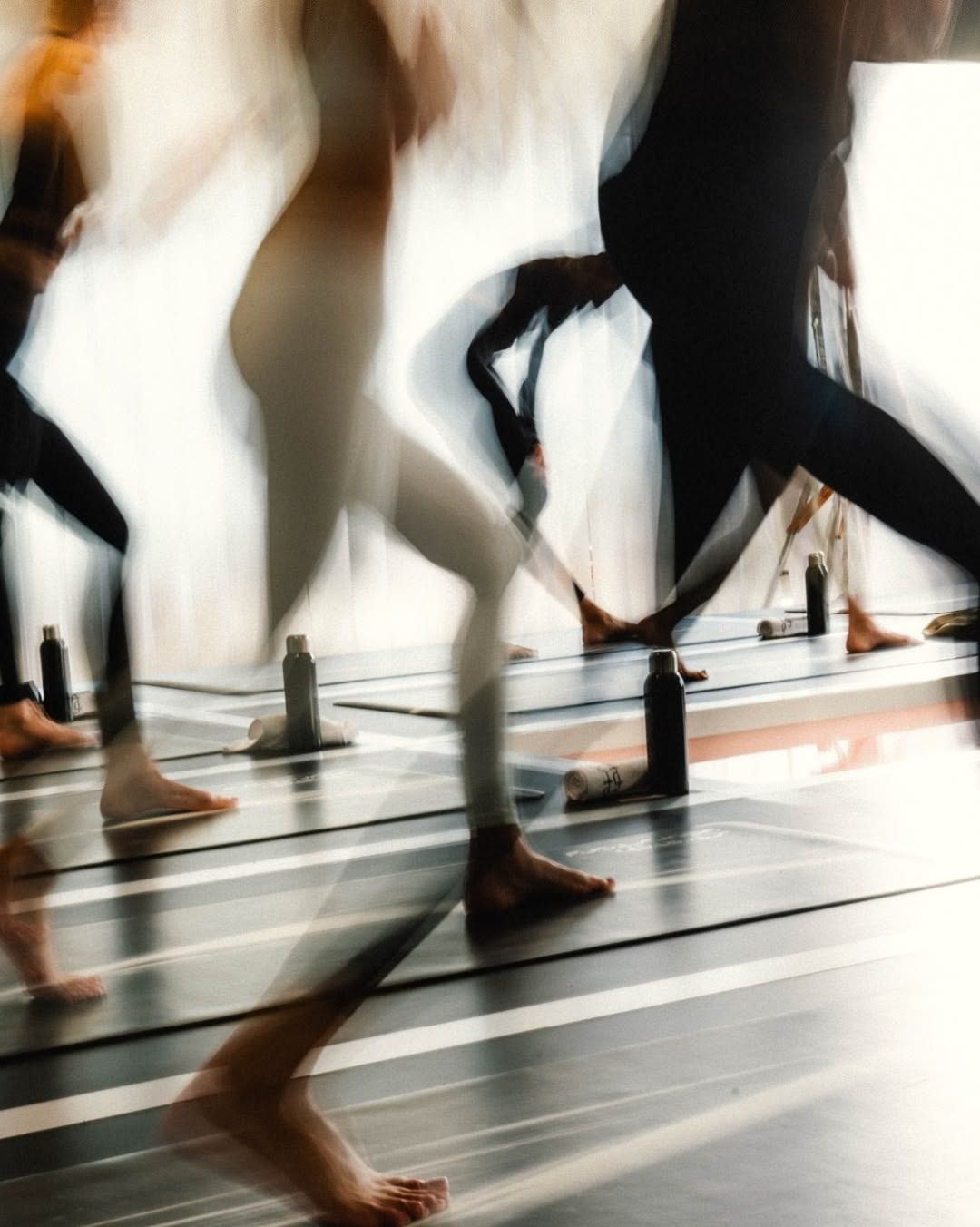 People practice yoga on mats beside water bottles