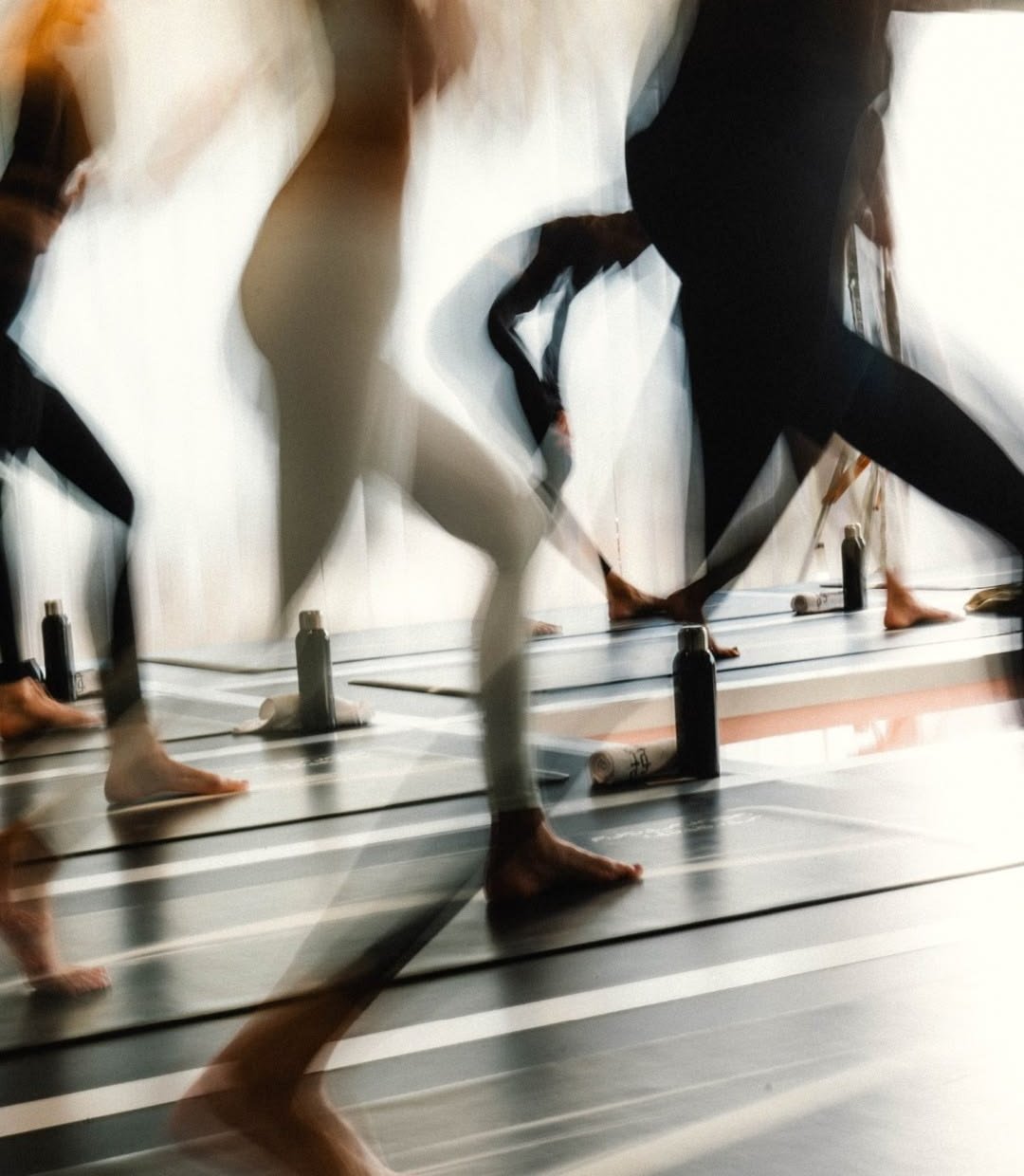 People practice yoga on mats beside water bottles