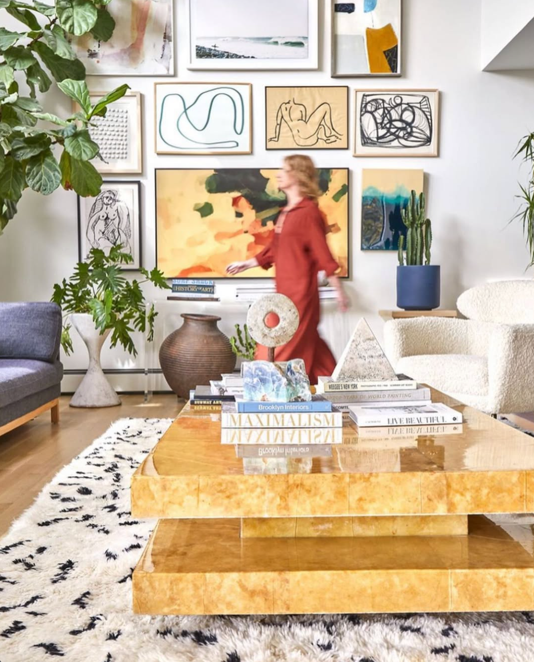 Woman walks through a living room filled with artwork and plants