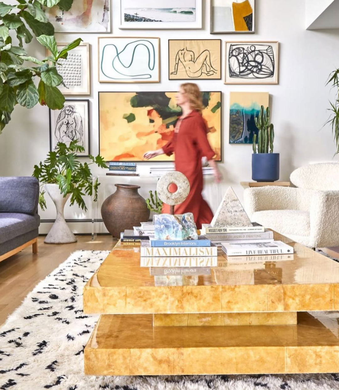 Woman walks through a living room filled with artwork and plants