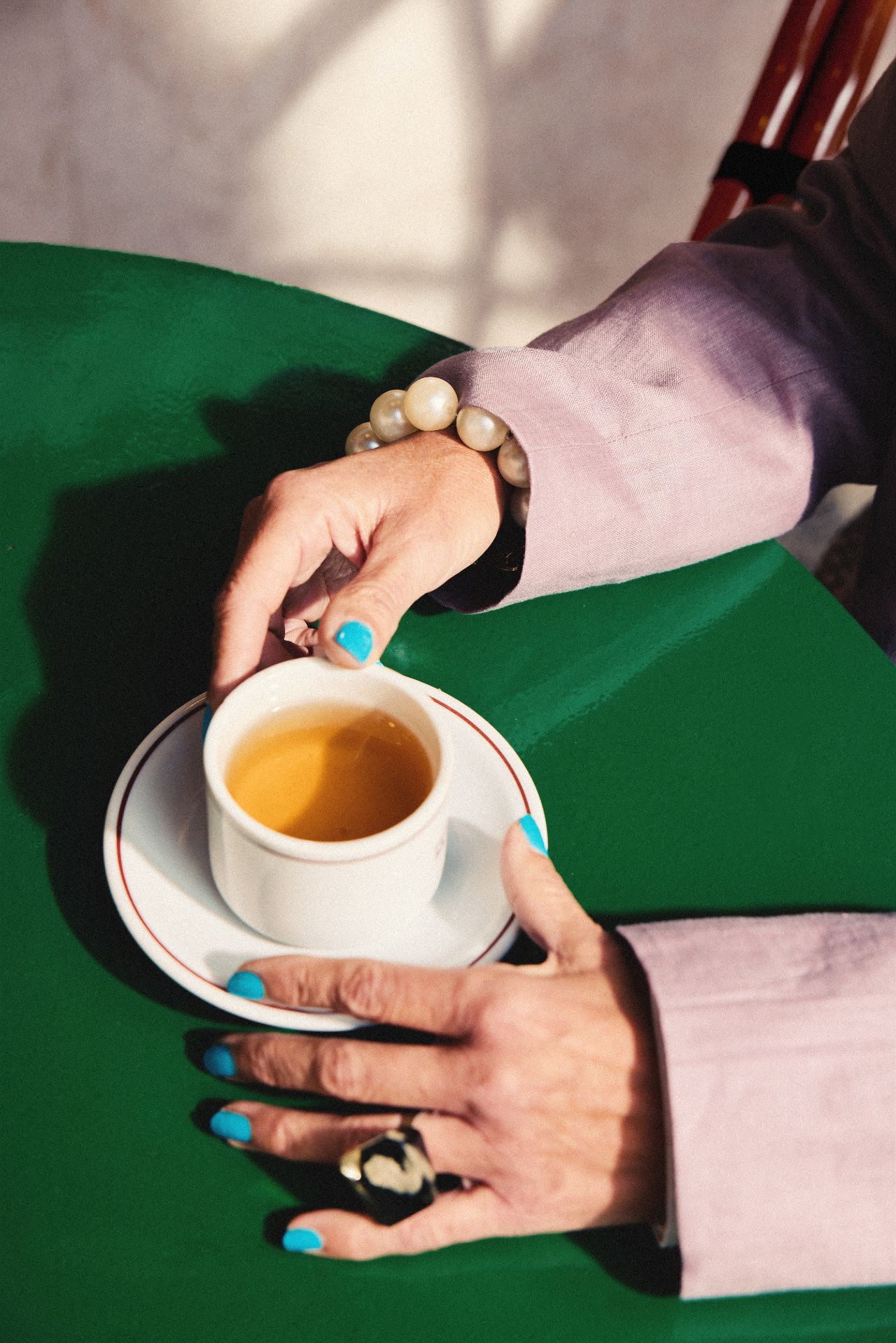Hands with turquoise nails hold a cup of tea