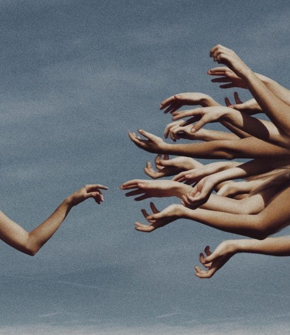 Many outstretched arms reach toward a single arm