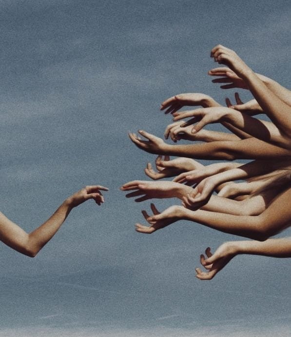 Many outstretched arms reach toward a single arm