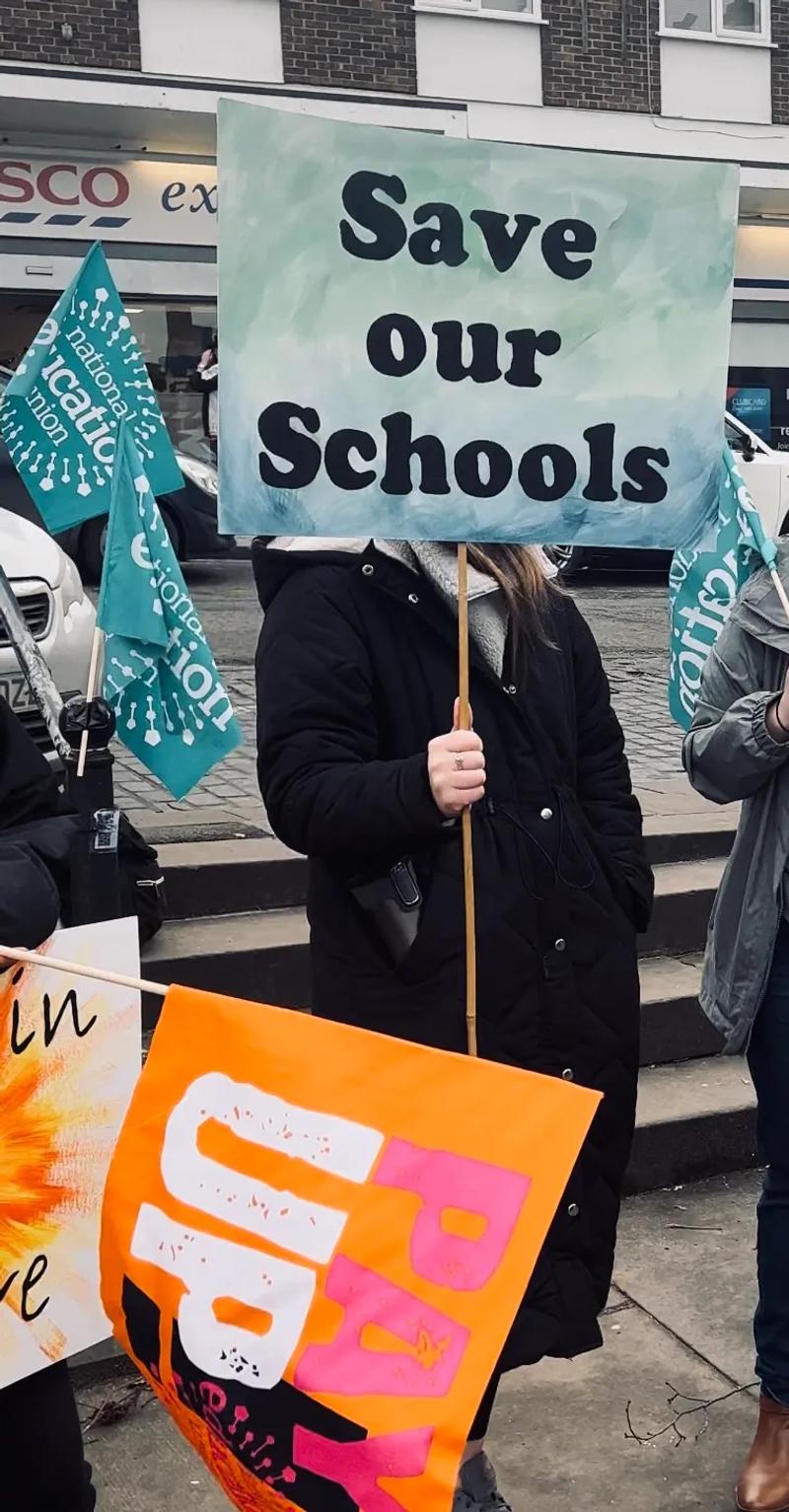 teacher holding sign that says save our schools