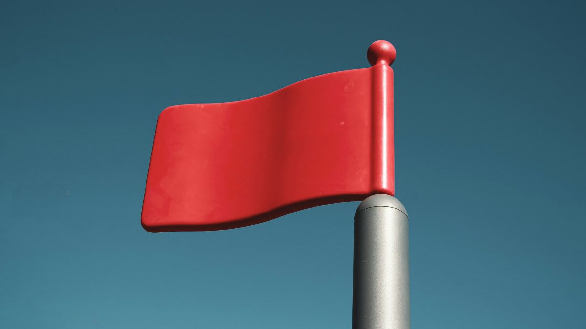 Red warning flag against a blue sky, representing concerns about gaps in Australia’s emergency alert system.