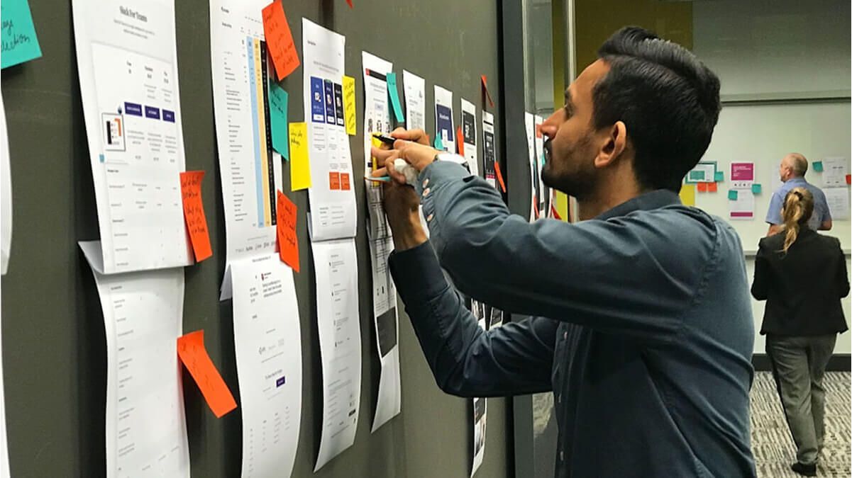 An AIrteam client collaborating on a piece of UX work by providing notes on a post it note.
