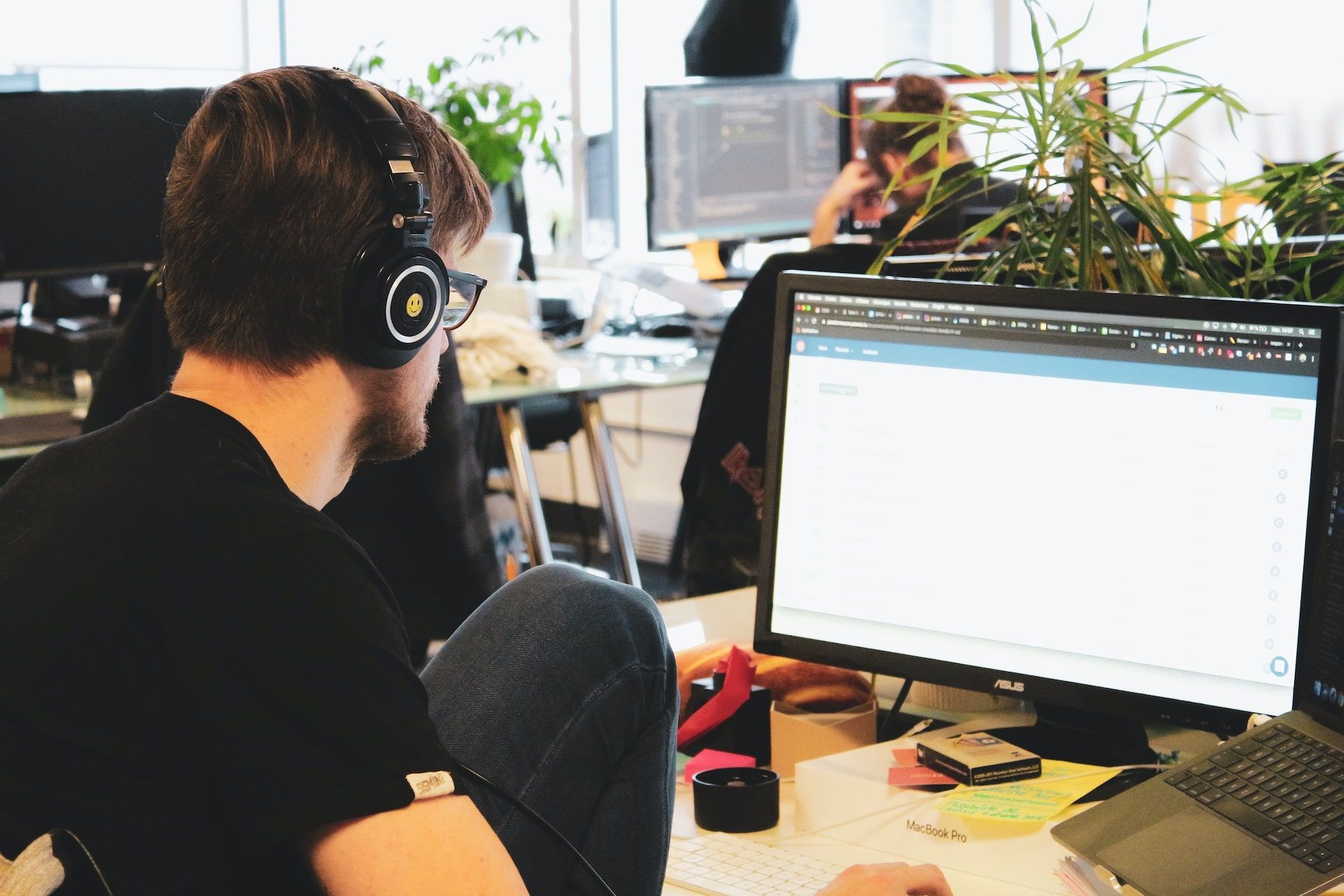 Software developer working on a laptop with his headphones on.