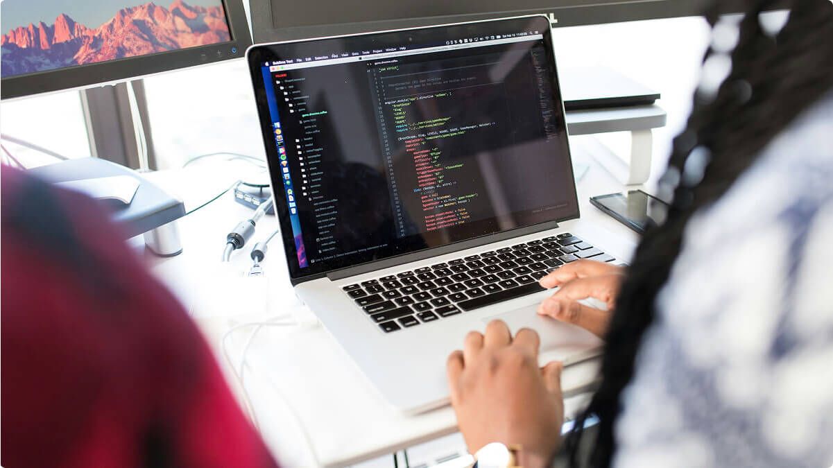 Person coding on a laptop, we can only see their hands.