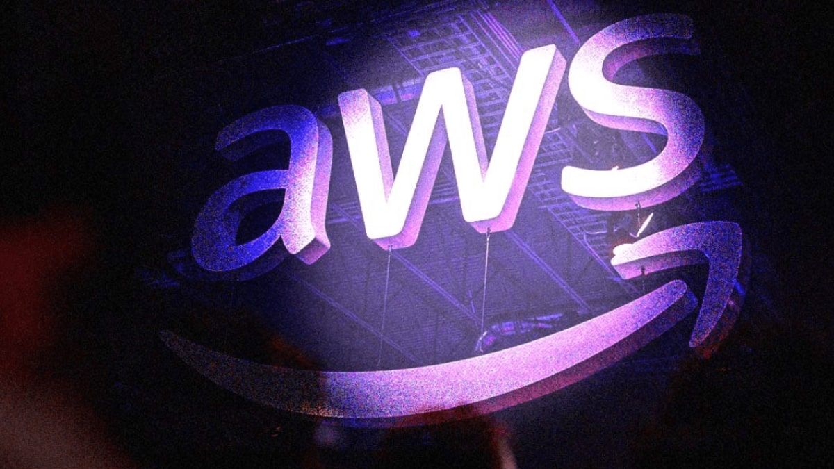 A glowing purple AWS logo illuminated on stage, representing Amazon Web Services.