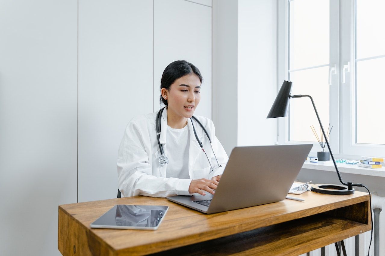 A doctor working on her laptop at her desk.