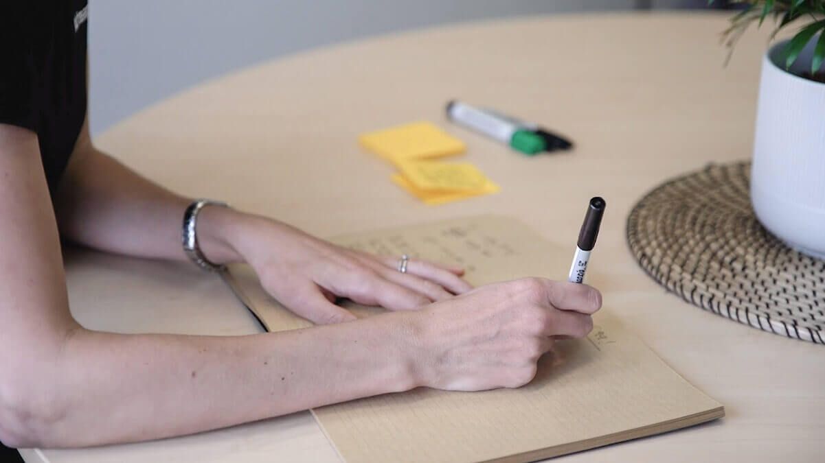 The hands of an Airteam team member writing about user experience on a piece of paper at her desk.